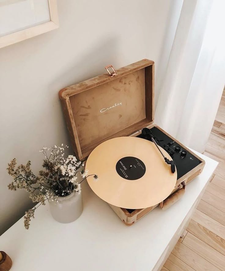 an old record player sitting on top of a table next to a potted plant