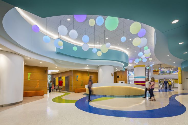 two people are standing in the lobby of a large building with colorful circles hanging from the ceiling