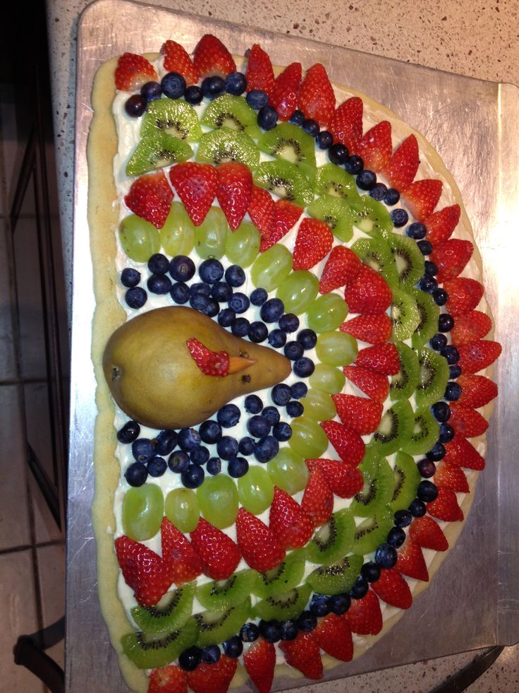 a fruit and vegetable pizza is decorated with kiwis, strawberries, blueberries, oranges, and pears