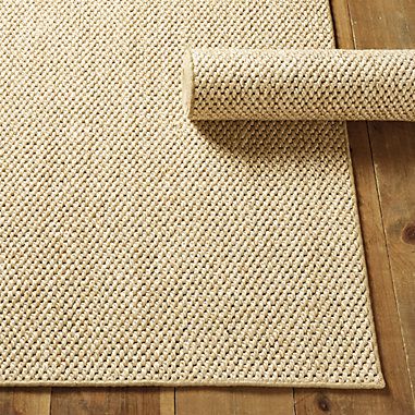 an area rug on top of a wooden floor next to a roll of paper and scissors