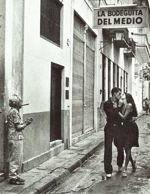 an old photo of two people kissing in front of a building with a sign that reads la bodeguita del medio