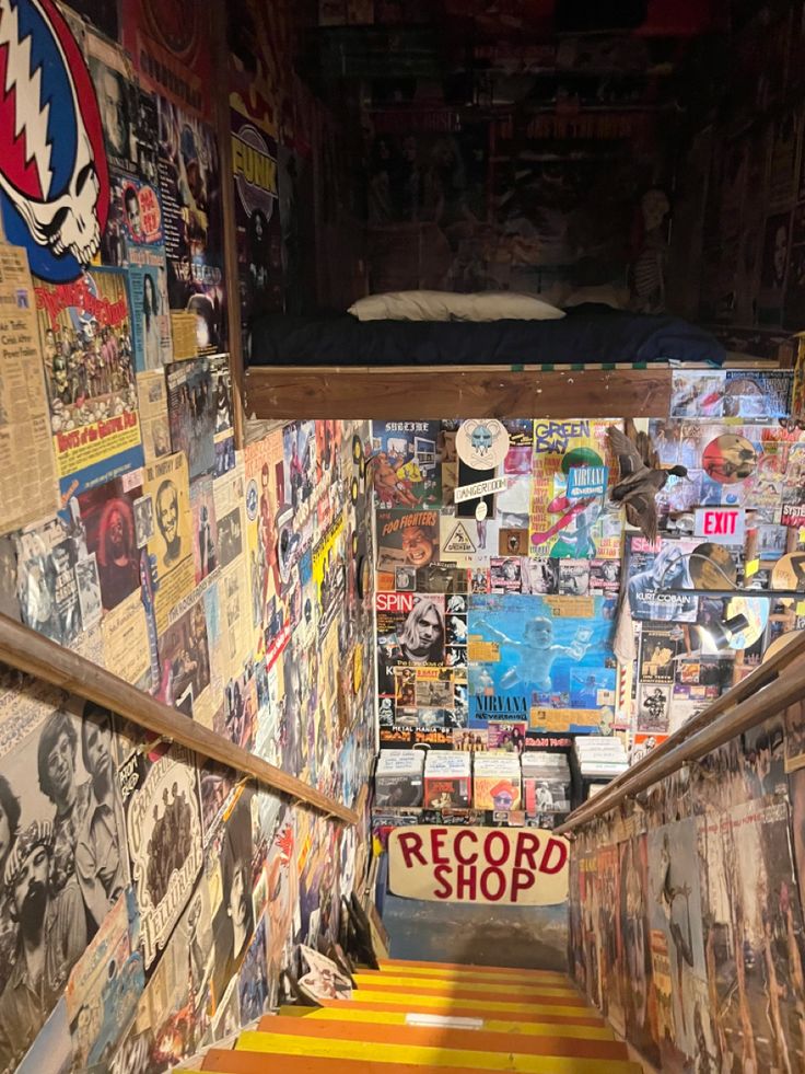 the stairs are covered with posters and stickers in an alleyway that has been turned into a bedroom