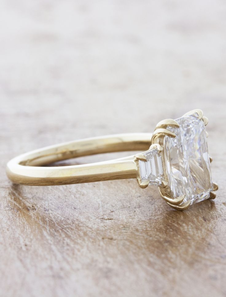 an engagement ring with a large diamond in the center on top of a wooden surface