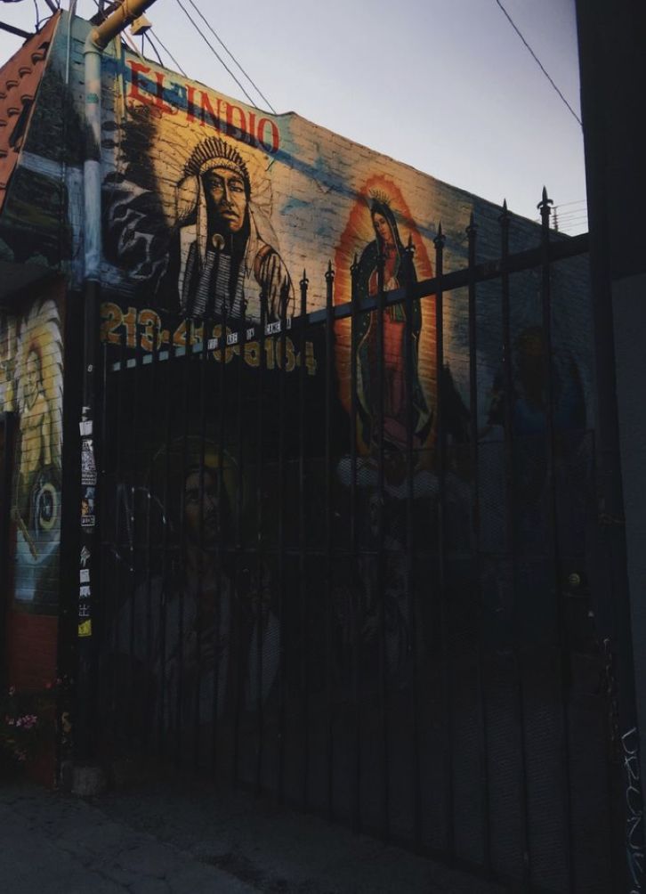 a large mural on the side of a building behind a fence with a light pole