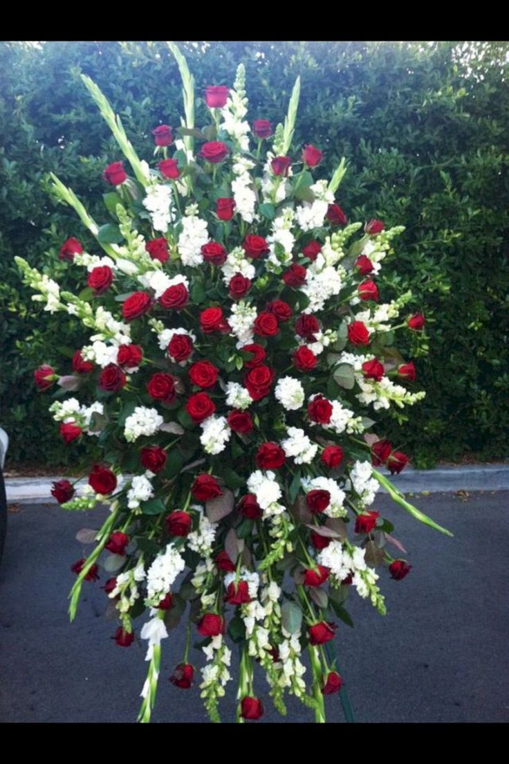 a bunch of red and white flowers are arranged in the shape of a wreath on top of a pole