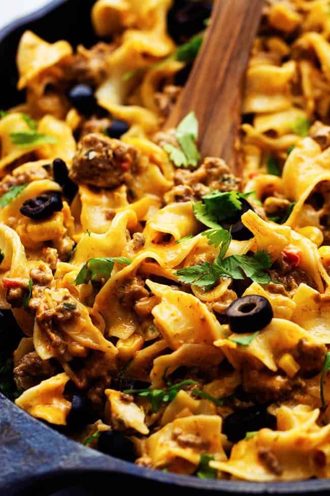 a skillet filled with pasta, meat and olives