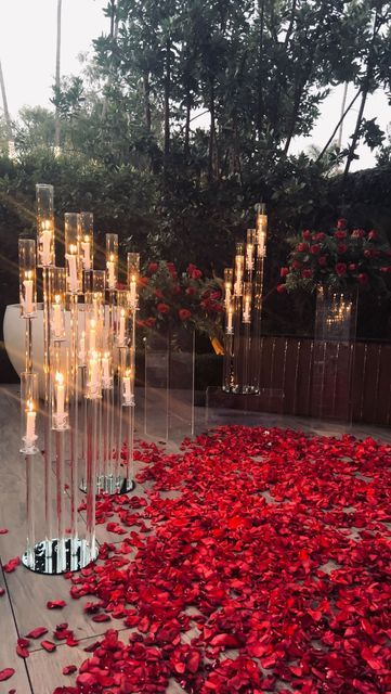 red rose petals on the ground in front of a glass sculpture with candles and lights