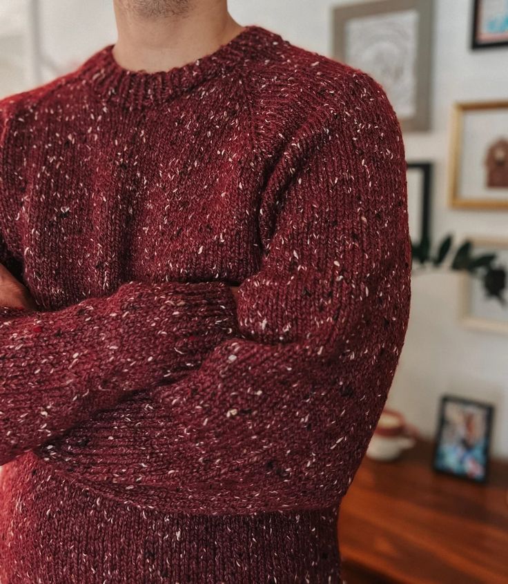 a man in a red sweater standing with his arms crossed