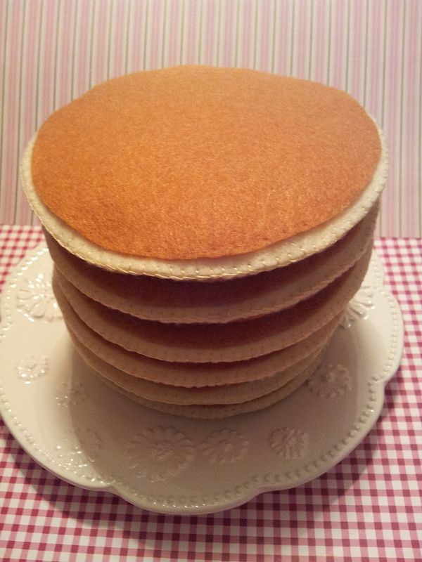 a stack of cake sitting on top of a white plate next to a red and white checkered table cloth