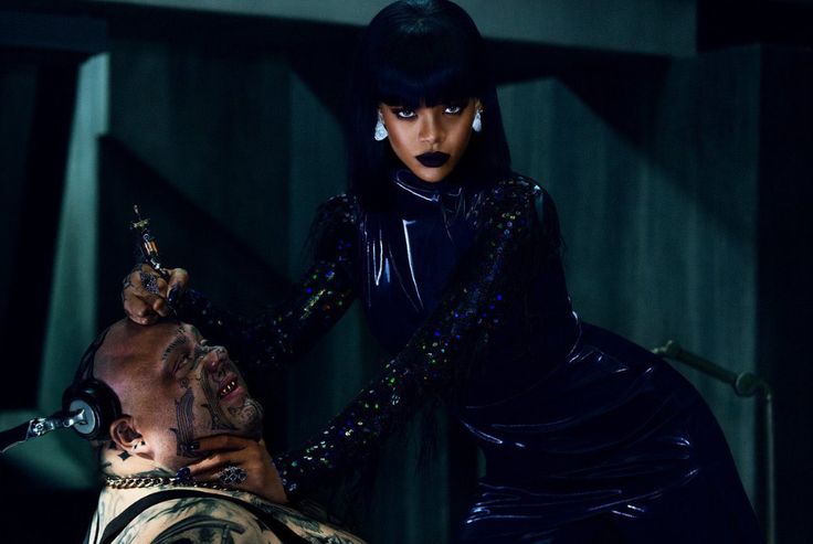 a woman is getting her hair done by a man in a black dress and headpiece