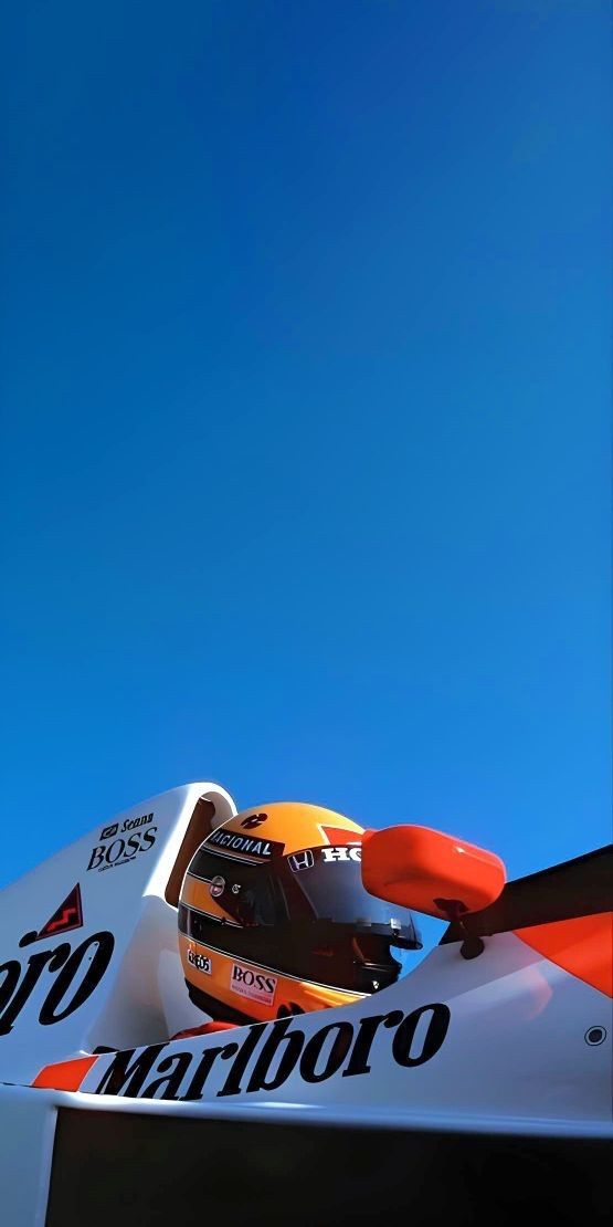 an orange and white race car sitting on top of a track under a blue sky