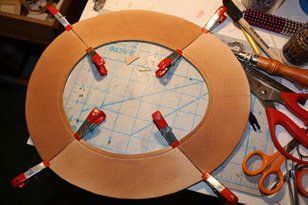 a wooden circle with scissors and other crafting supplies around it on top of a table