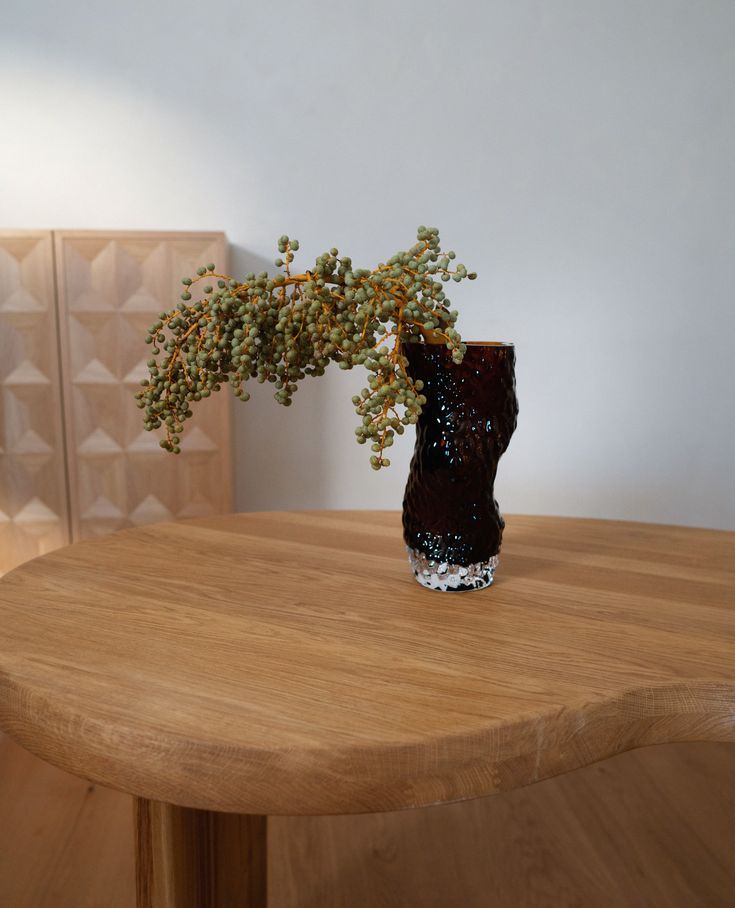 there is a vase with some flowers in it sitting on the table next to a wall