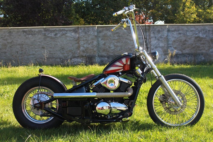 a motorcycle parked in the grass near a stone wall