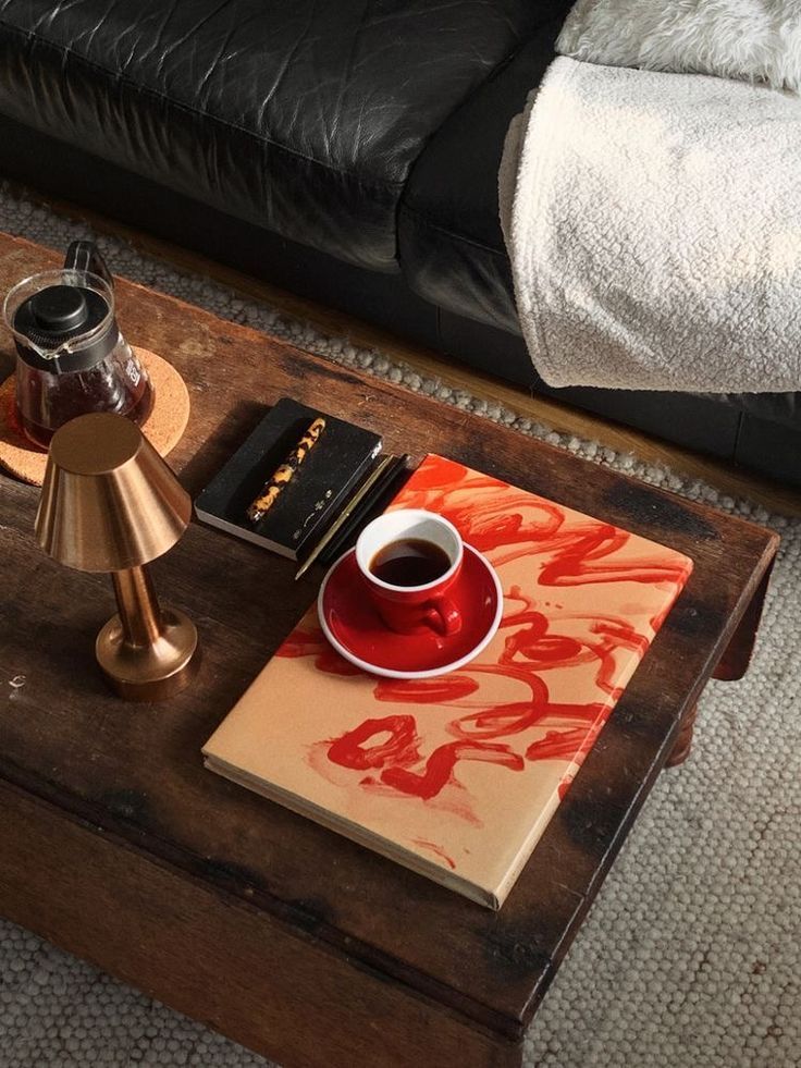 a coffee table with a book and a lamp on it in a living room next to a couch