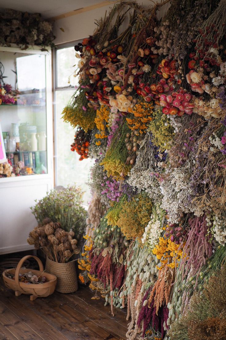 dried flowers are hanging on the wall next to baskets