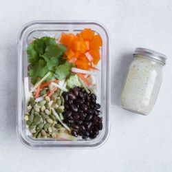 a plastic container filled with different types of food next to a jar of seasoning