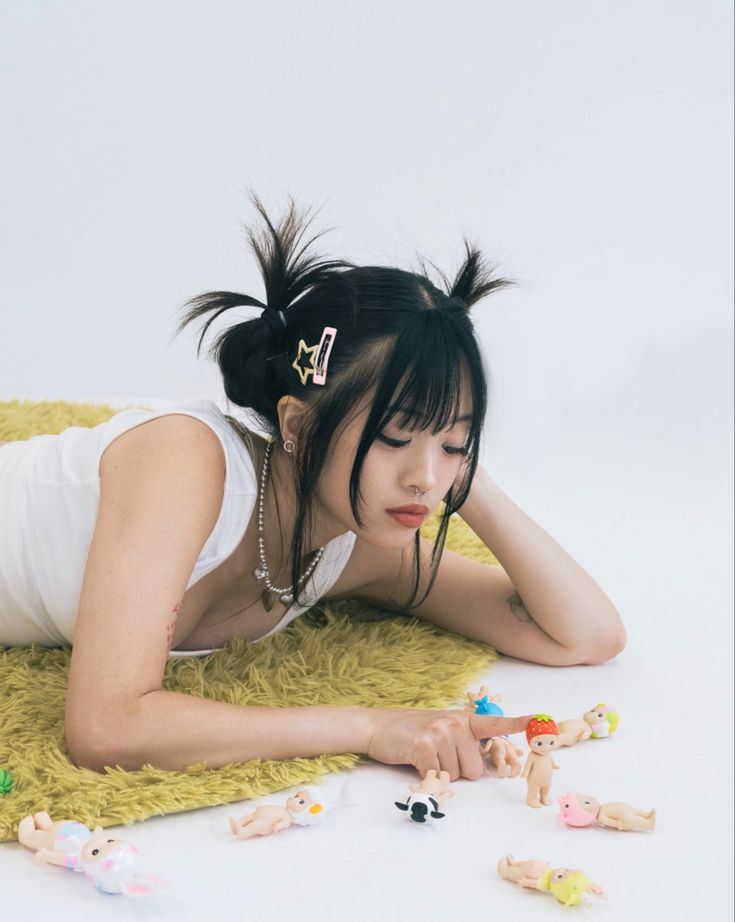 a woman laying on top of a yellow blanket next to toy figures and toys in front of her