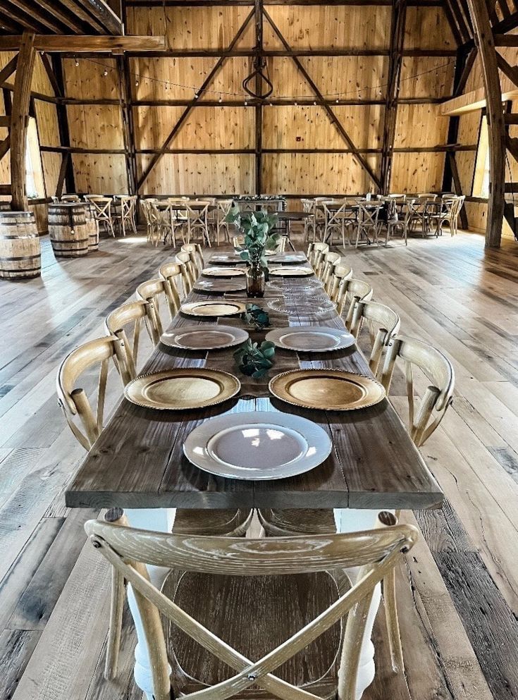 a long table set with plates and place settings in a large room filled with wooden walls