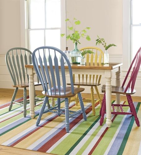 three chairs and a table in a room with striped rugs on the floor next to windows