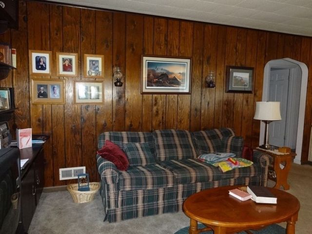 a living room with wood paneling and plaid couches in it's corner