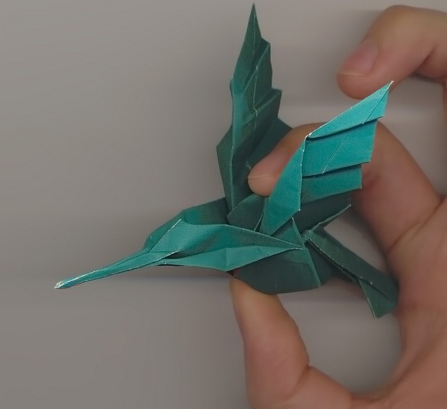 someone is holding an origami bird in their hand