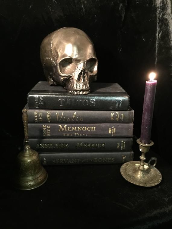 a stack of books with a skull sitting on top of them next to a candle