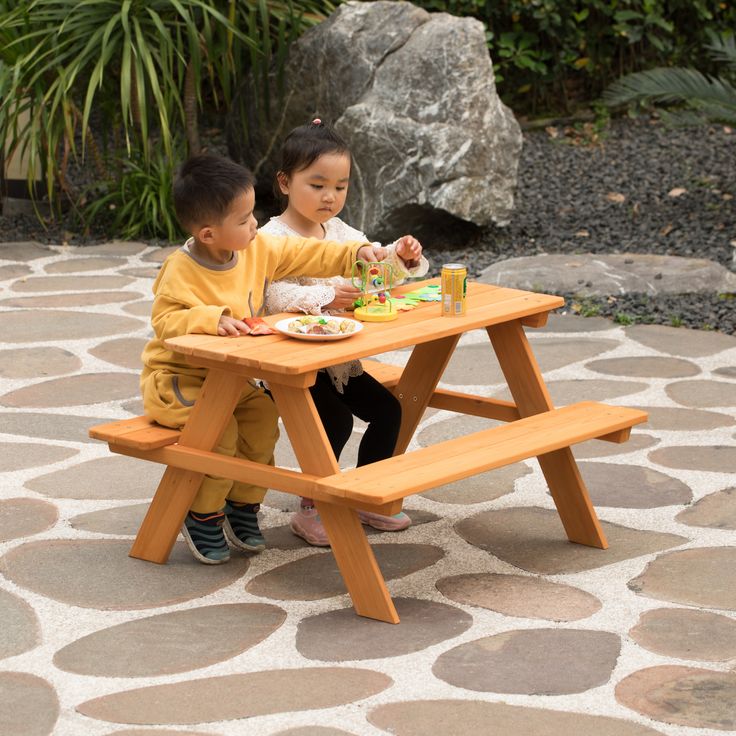 two children are sitting at a picnic table