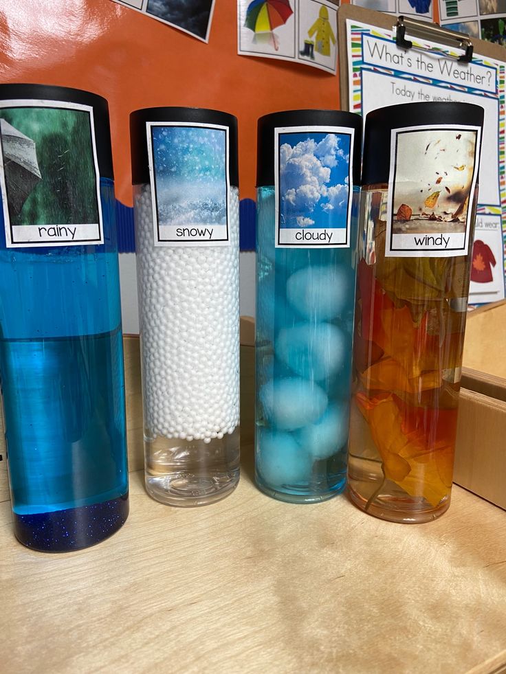 three vases filled with blue and white balls on top of a wooden table next to pictures