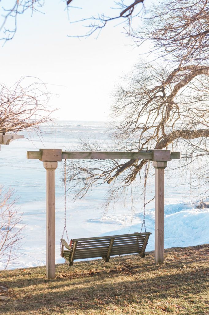 a wooden bench sitting on top of a grass covered field next to a body of water