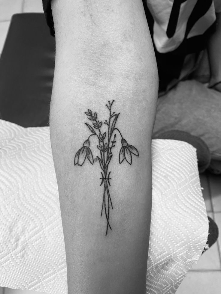 a black and white photo of a flower tattoo on the leg