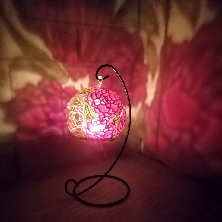 a pink lamp sitting on top of a table next to a flowery wallpaper