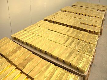 several stacks of gold bars sitting on top of each other in a storage room with white walls