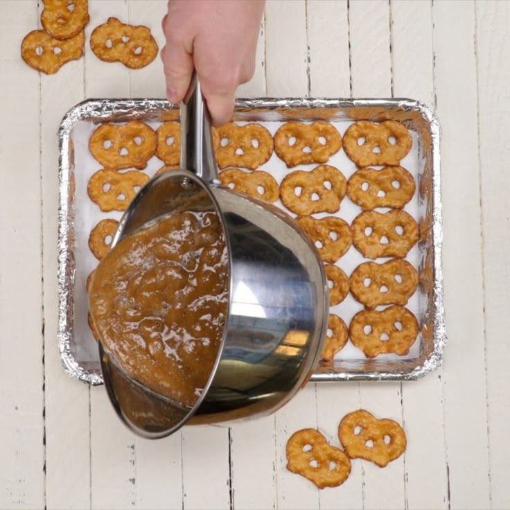 a person is scooping some food out of a pan and onto a tray with pretzels