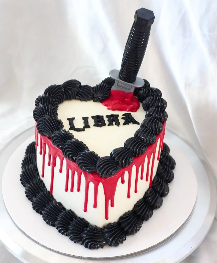 a heart shaped cake with a knife sticking out of the top and blood dripping on it