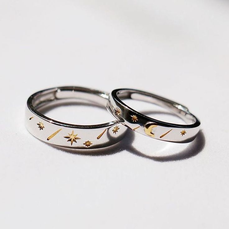 two wedding rings with gold stars and moon designs on them sitting next to each other