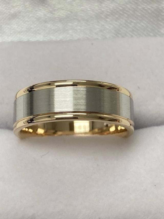 two tone gold and silver wedding ring on white cloth with satin material in the background