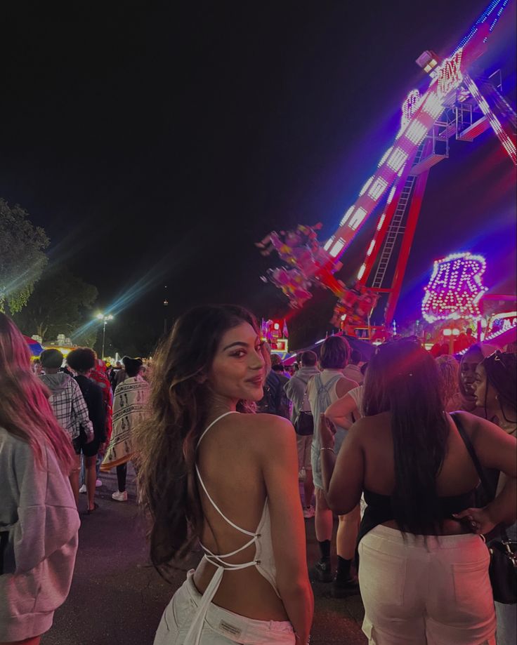 a woman standing in front of a carnival ride at night