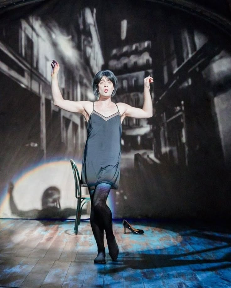 a woman standing on top of a wooden floor in front of a wall with lights