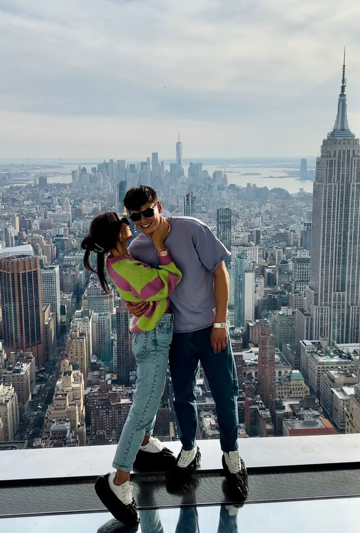 a man and woman standing on top of a building in new york city, kissing