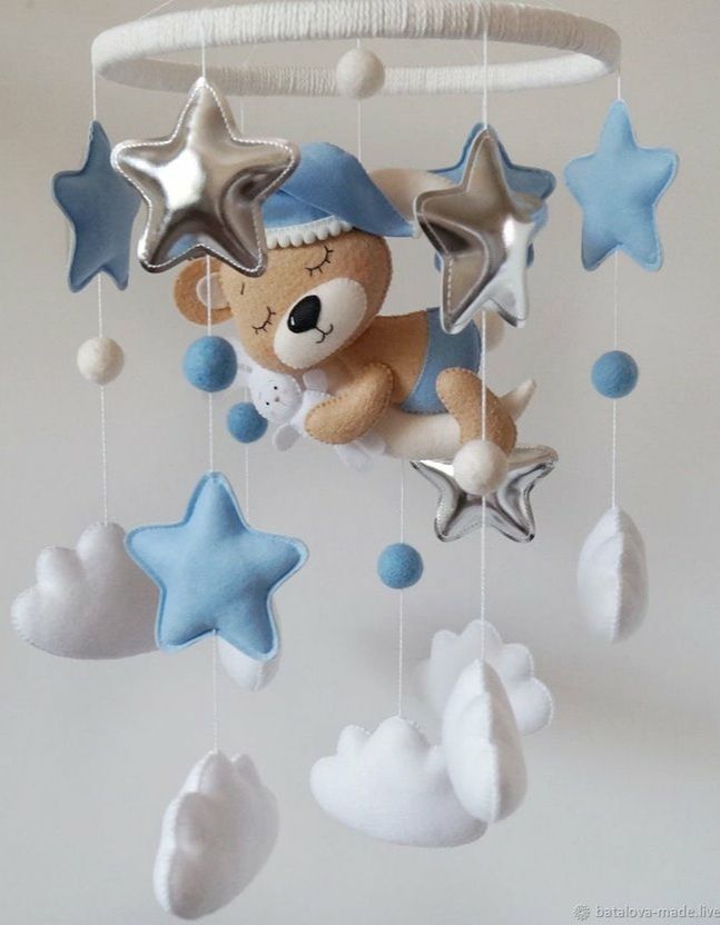 a teddy bear hanging from a mobile in the shape of stars