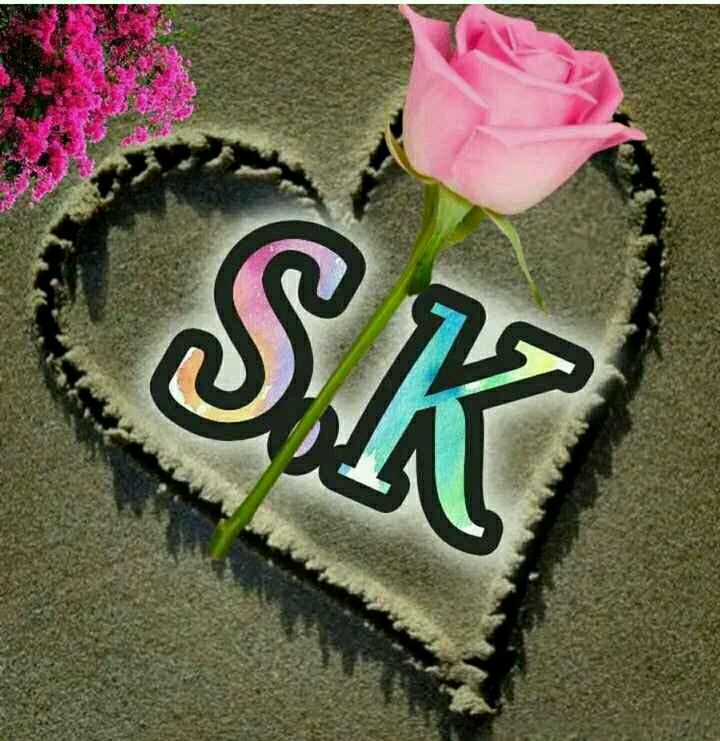 a pink rose sitting on top of a heart shaped piece of paper with the letter k in it