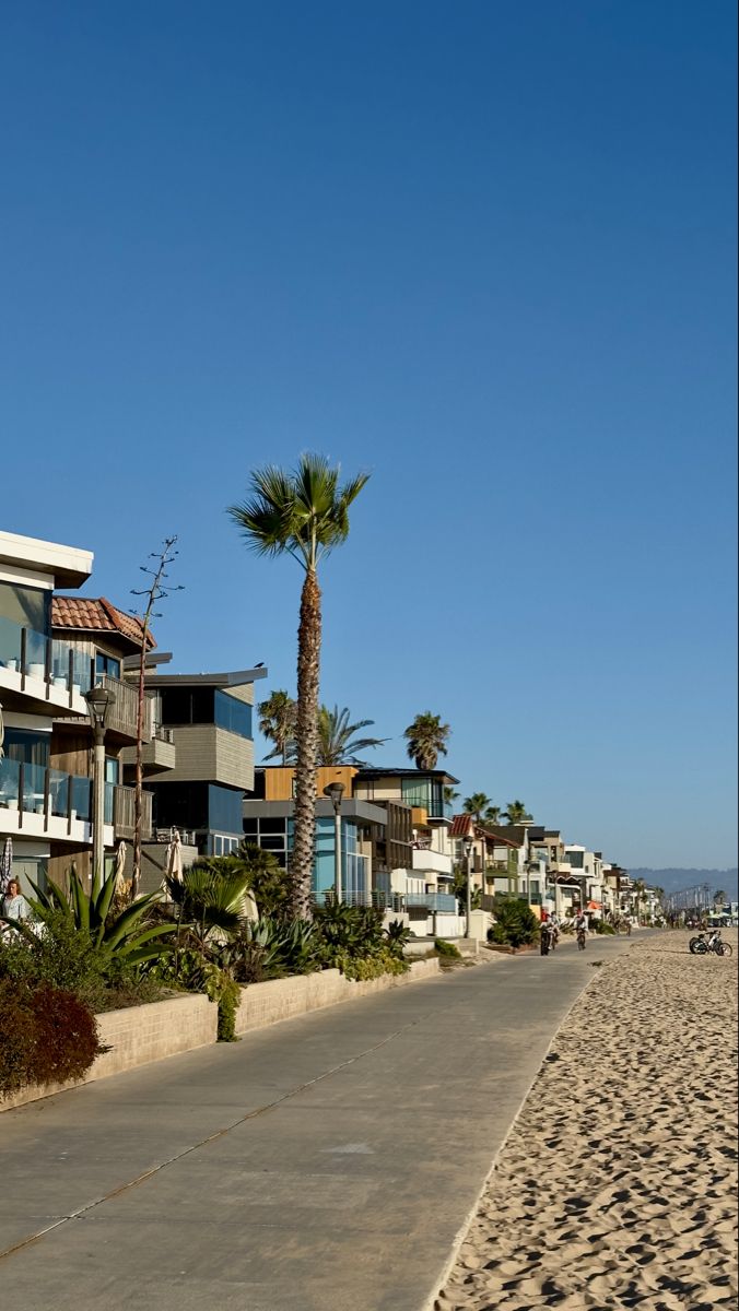 the beach is lined with palm trees and apartment buildings on either side of the road