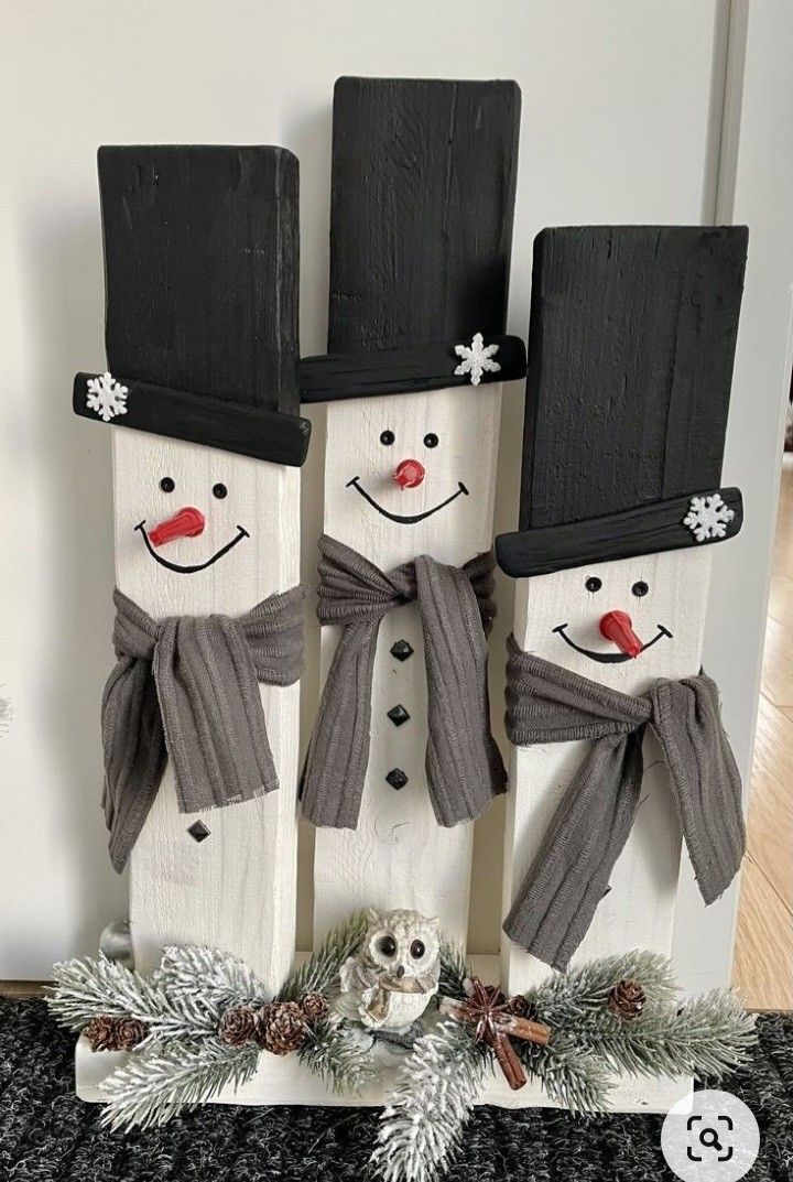 three snowmen made out of wooden planks with hats and scarfs