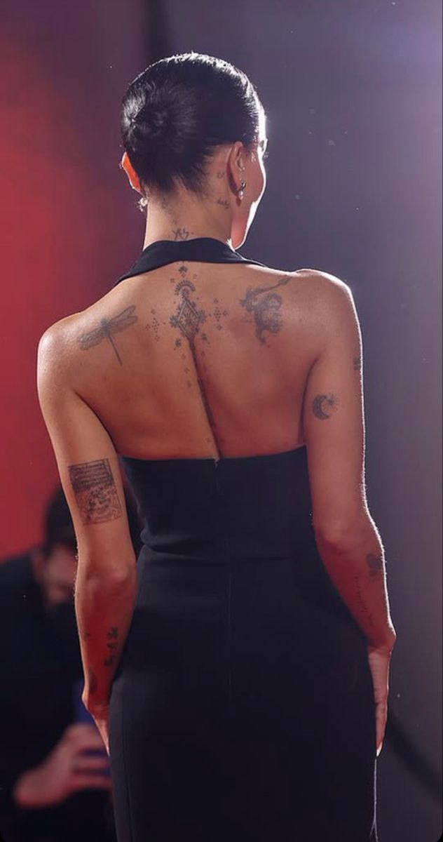 a woman in a black dress with tattoos on her back