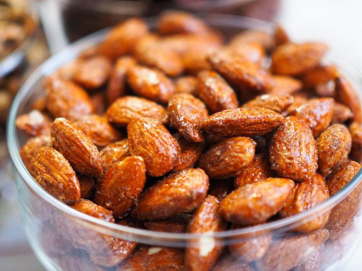 a bowl filled with almonds sitting on top of a table next to other nuts