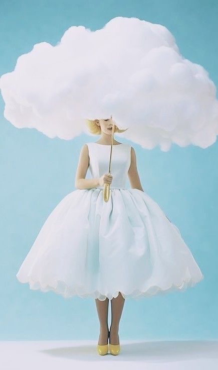 a woman wearing a white dress and holding a yellow umbrella under a cloud shaped like a human head