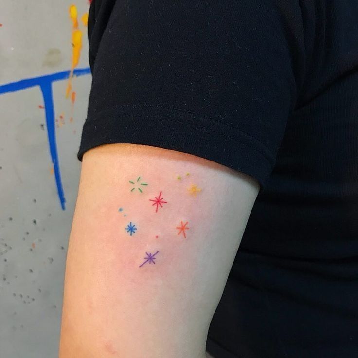 a woman's arm with stars on it and the word love written in white ink