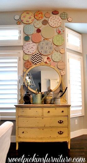 a dresser with a mirror on top of it in front of a wall covered in circles