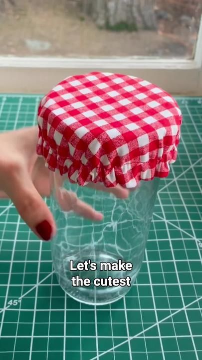 a person is holding up a red and white checkered hat on top of a table